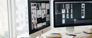 A sleek modern office setup featuring dual monitors, Apple devices, and creative decor in an indoor workspace.